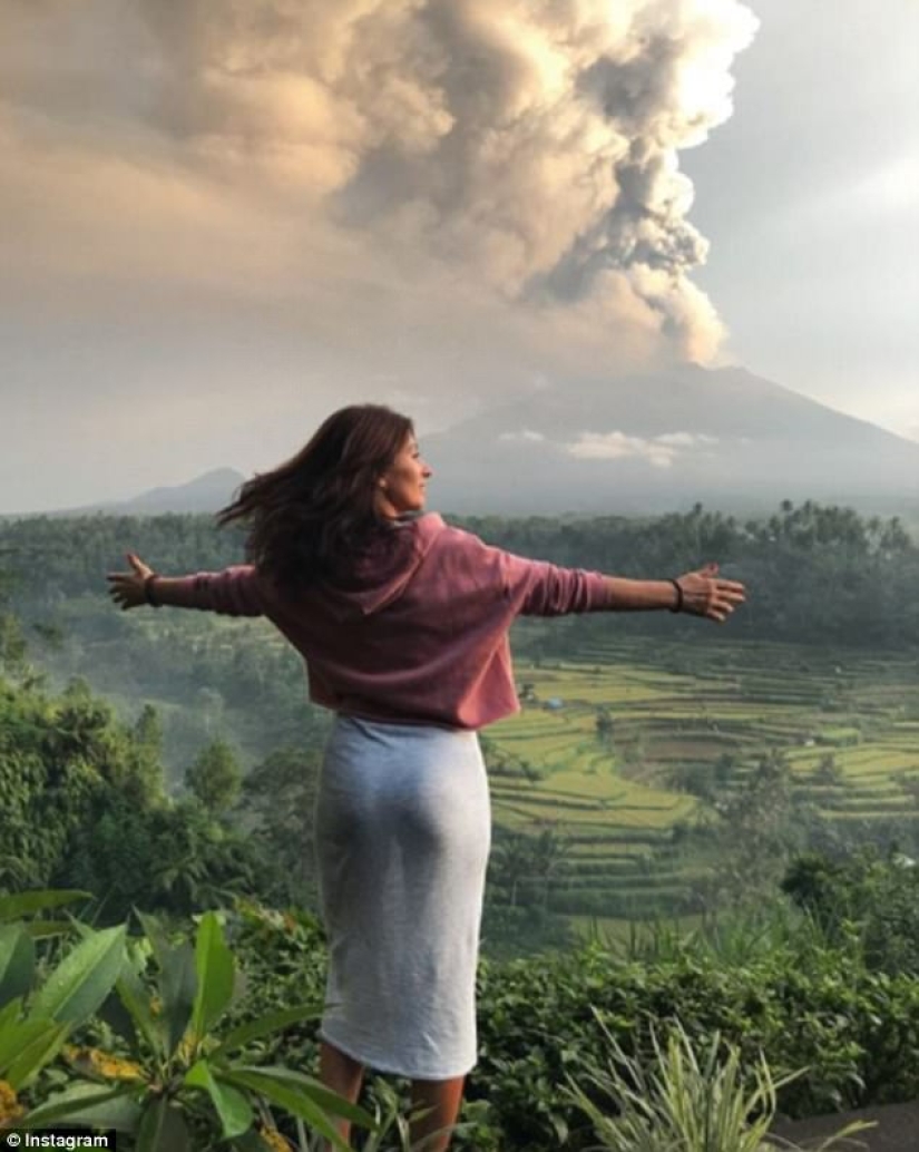 Mientras los residentes de Bali se alejan del volcán, los turistas son fotografiados con el telón de fondo de las emisiones de cenizas Mientras los residentes de Bali se alejan del volcán, los turistas son fotografiados con el telón de fondo de las emisiones de cenizas