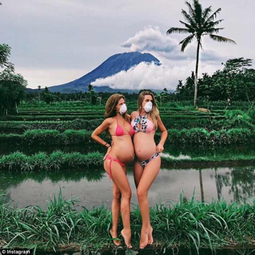 While the residents of Bali are moving away from the volcano, tourists are photographed against the background of ash emissions