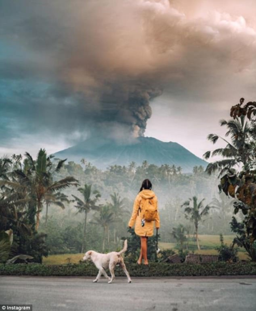 While the residents of Bali are moving away from the volcano, tourists are photographed against the background of ash emissions
