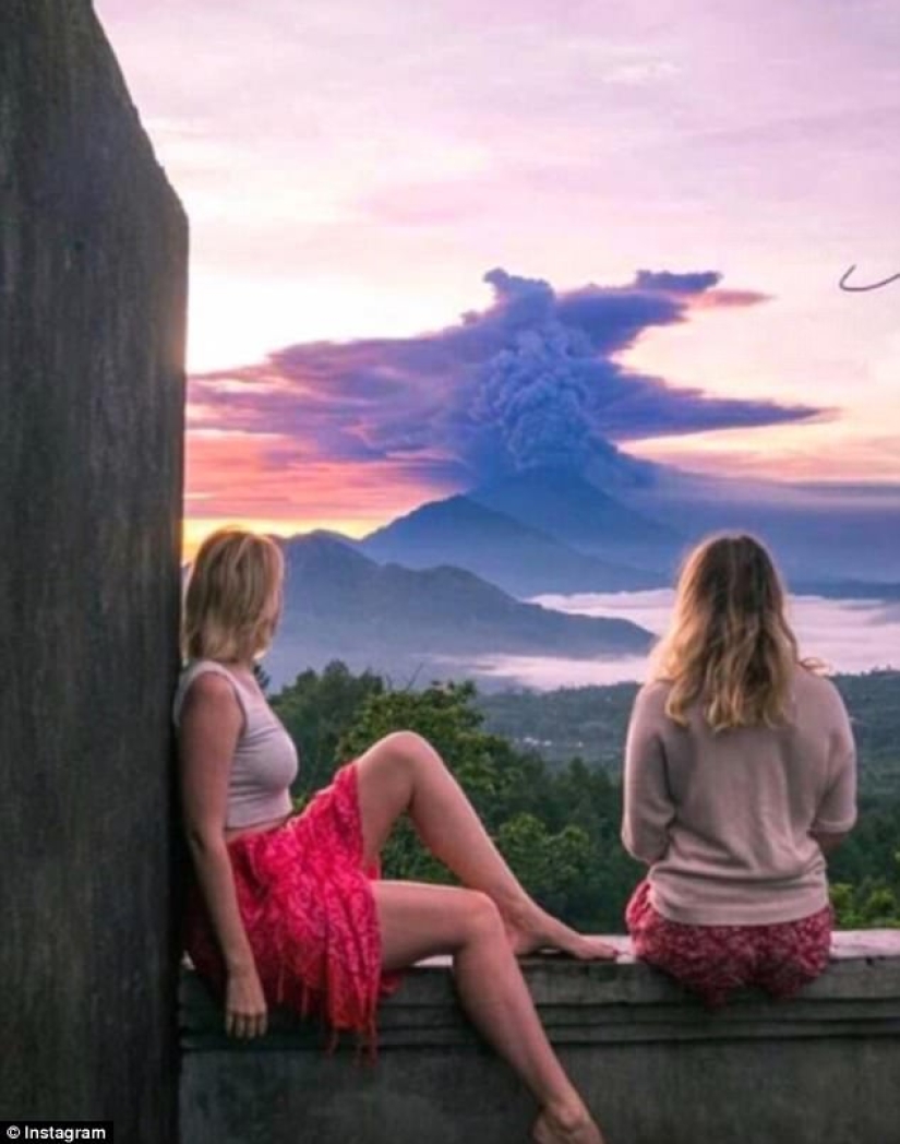 While the residents of Bali are moving away from the volcano, tourists are photographed against the background of ash emissions