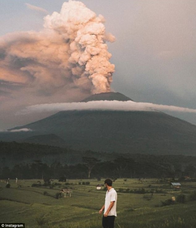 While the residents of Bali are moving away from the volcano, tourists are photographed against the background of ash emissions