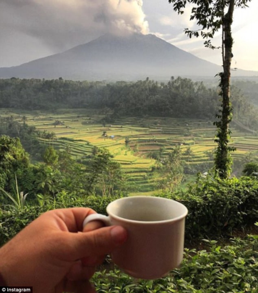 While the residents of Bali are moving away from the volcano, tourists are photographed against the background of ash emissions