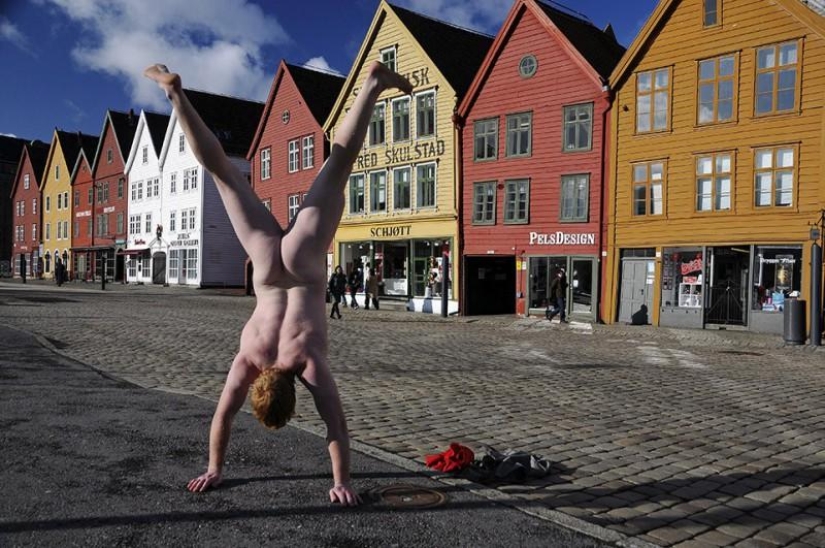 An exhibitionist traveler takes a naked photo against the backdrop of nature and city attractions