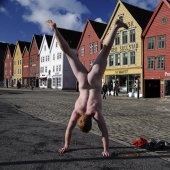 An exhibitionist traveler takes a naked photo against the backdrop of nature and city attractions