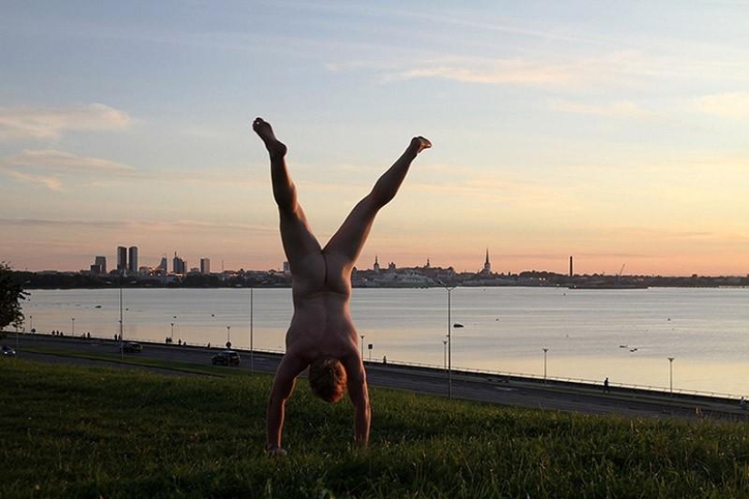 An exhibitionist traveler takes a naked photo against the backdrop of nature and city attractions