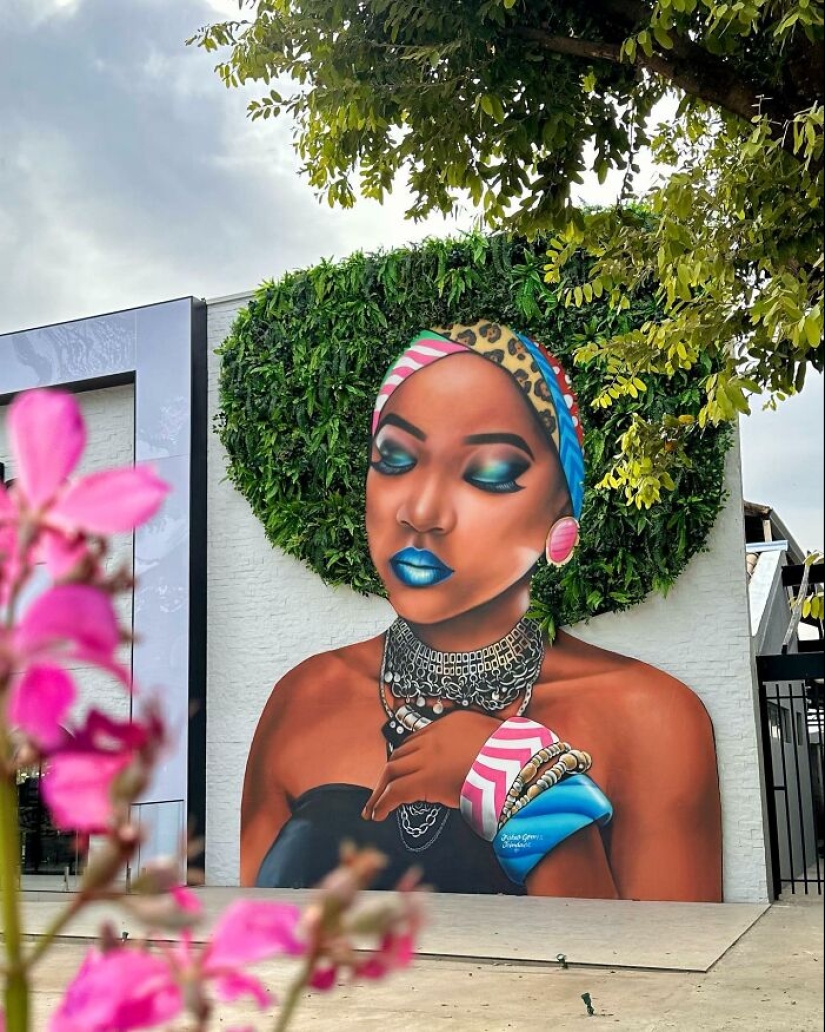 Artista callejero continúa pintando retratos en paredes junto a árboles que también sirven como cabello