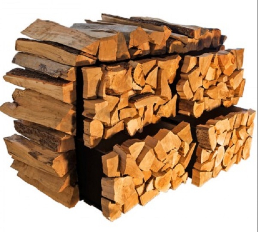 There is grass in the yard, firewood on the grass