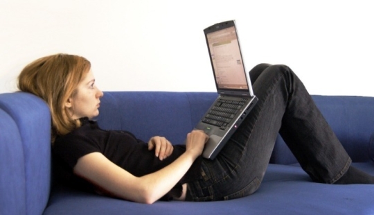 Why is it harmful to work at a laptop lying down